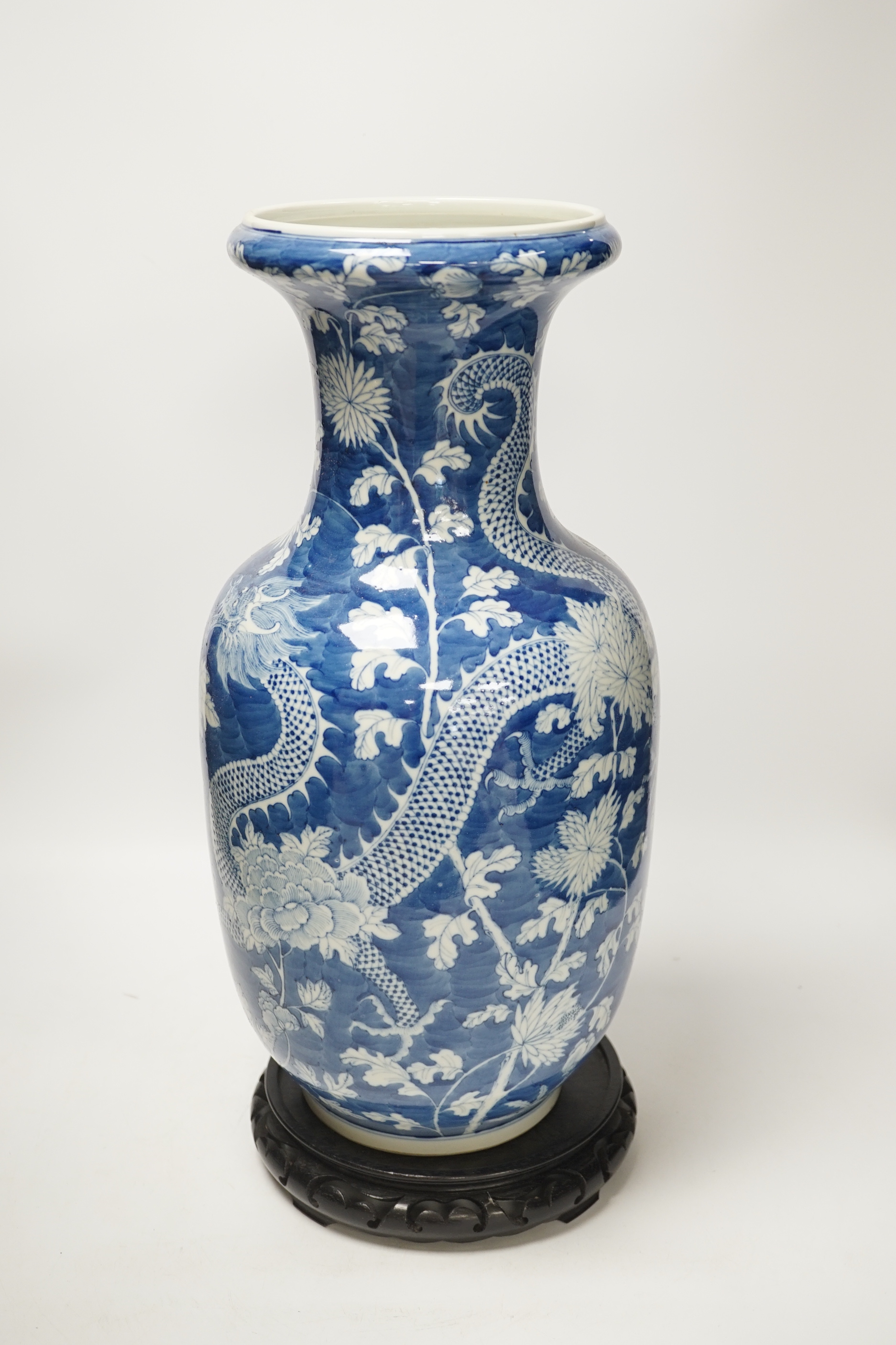 A Chinese blue and white baluster vase decorated with dragons and flowers together with an unassociated carved hardwood stand, 44cm high